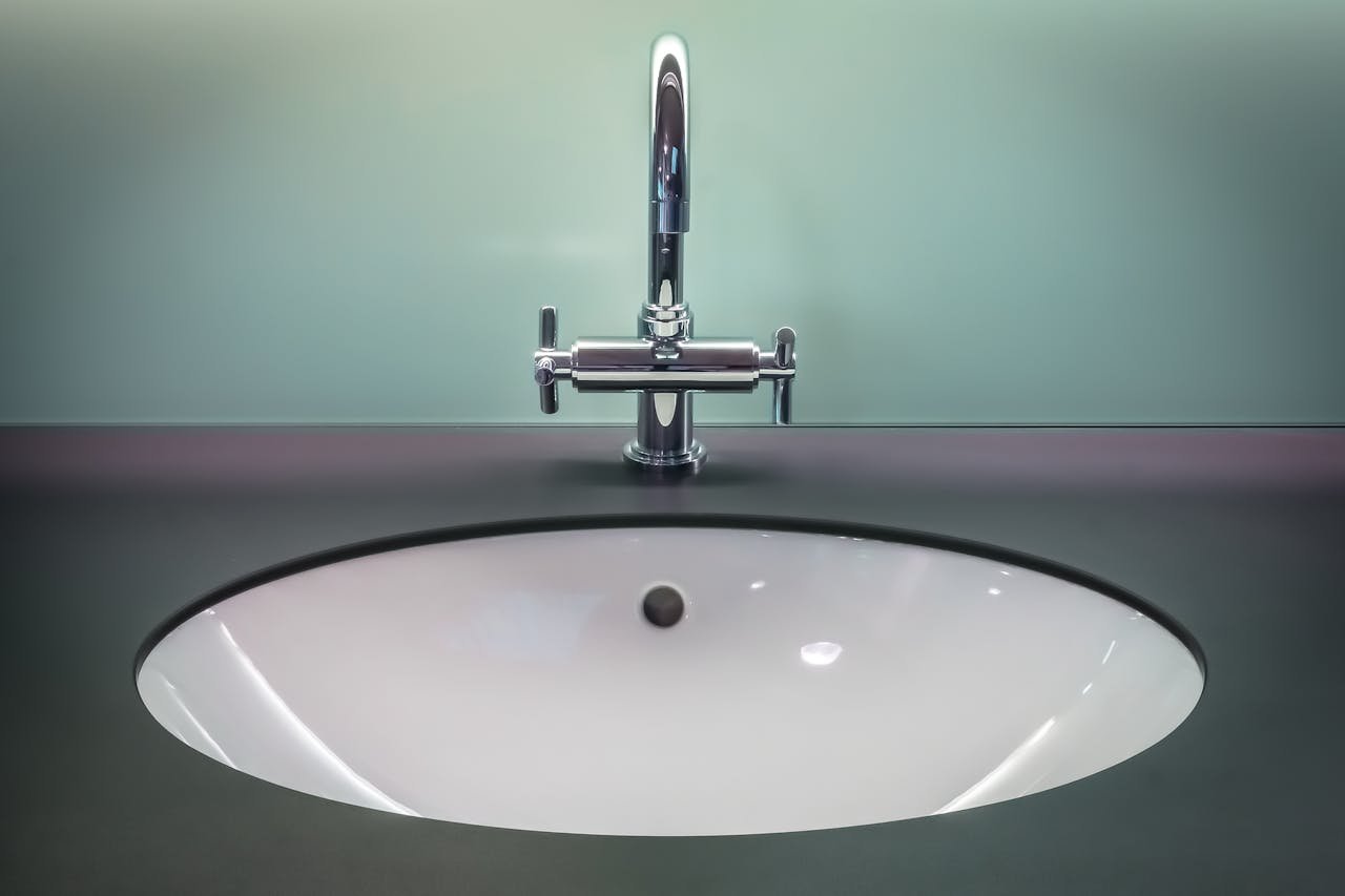 A sleek modern bathroom sink with a shiny stainless steel faucet on a dark vanity.